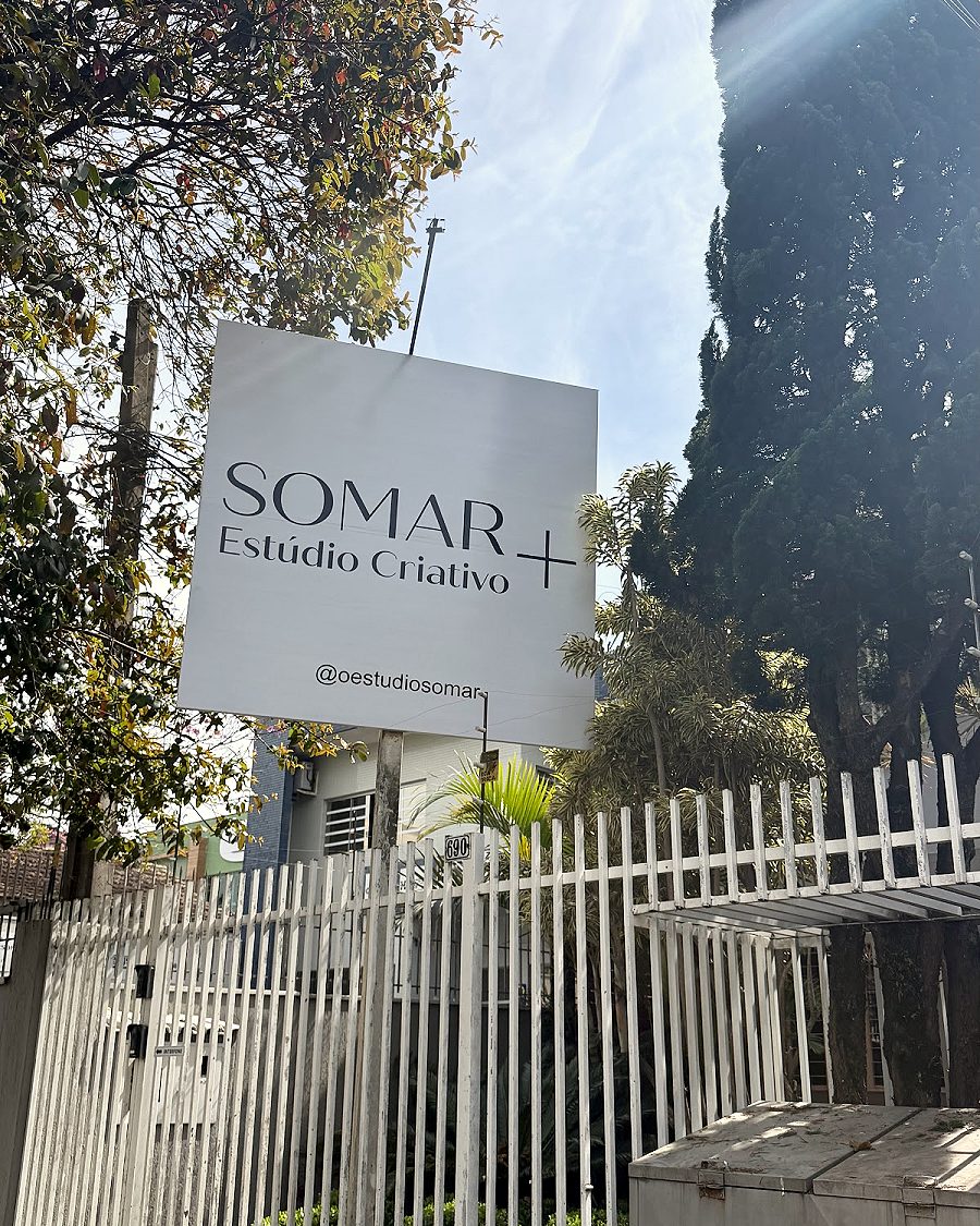 Fachada do SOMAR + Estúdio Criativo, com a placa no portão branco